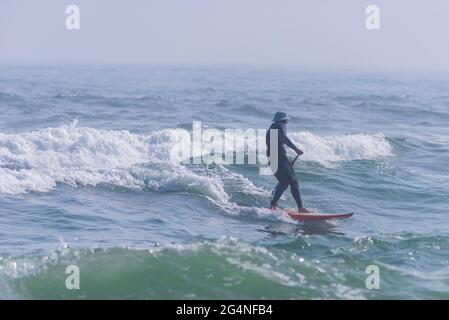 Am 26. März 2021 surft ein Mann in der Nähe des Strandes an der Johnson Beach National Seashore in Florida. Stockfoto