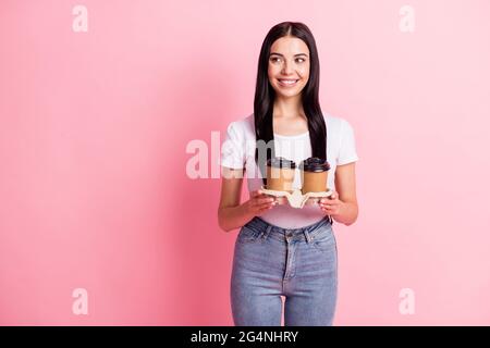 Portrait von attraktiven fröhlichen Mädchen hält in den Händen mit zwei Pappbecher Latte kopieren Raum isoliert über rosa Pastellfarben Hintergrund Stockfoto