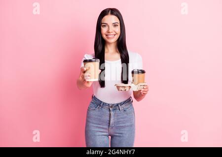 Portrait von attraktiven fröhlichen Mädchen bringen mit zwei Pappbecher geben Ihnen Latte laden isoliert über rosa Pastellfarben Hintergrund Stockfoto