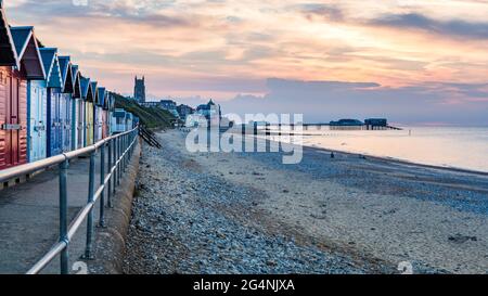 Der Pier ragt im Juni 2021 von der Küste Cromers ab, während die farbenfrohen Strandhütten den Vordergrund einnehmen. Stockfoto