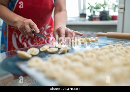 Eine Frau macht hausgemachte Knödel in der Küche am Tisch. Stockfoto