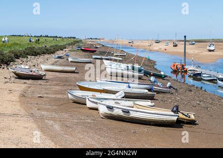 Boote auf dem Kanal nach Wells liegen am Sea Quay, der bei Ebbe unter blauem Himmel in Norfolk im Juni 2021 gesehen wird. Stockfoto