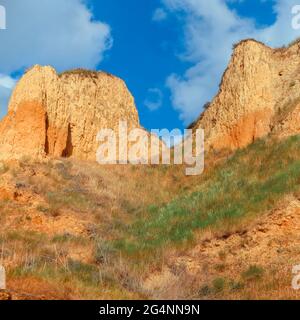 Blick auf die Landschaft von Clay Cape Cliffs. Grünes Gras, Rasenflächen an Hängen von Tonbergen gegen blauen Himmel. Die Hügel der Berge und die Hänge des Kaps sind Stockfoto