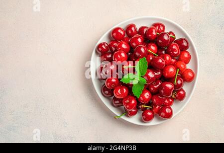 Reife Kirschen auf einem Teller auf einem rosa Hintergrund mit Platz zum Kopieren. Draufsicht. Stockfoto