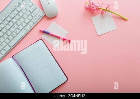 Rosafarbener Schreibtisch. Arbeitsbereich Bürotisch mit Computertastatur und Maus Notizblock Schreibwaren. Schreibtisch mit Schreibtisch und Kopierer in Pink Stockfoto