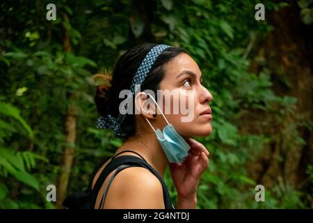 Lateinische Frau, die mit einer Covid-19 Maske mitten in der Natur unterwegs ist Stockfoto