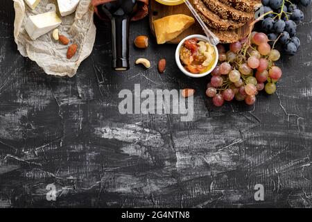 Food Snacks Zutaten verschiedene Käsesorten auf dunklem Beton-Hintergrund. Zusammensetzung von Wein und Käse. Mediterrane Küche Essen Getränke Gastronomie Stockfoto