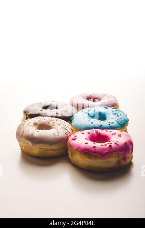Bunte Donuts auf isoliertem weißem Hintergrund. Süßer Teig gefüllt mit Marmelade, Schokolade, überzogen mit Zuckerfudge mit Streuseln. Textkopie Stockfoto