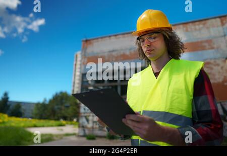 Ein männlicher Unternehmer in Harthut inspiziert verlassene Gebäude. Stockfoto
