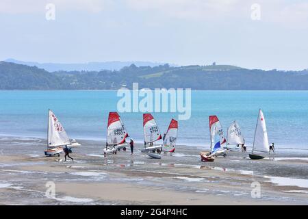 Segeljollen verschiedener Klassen werden für das Training am flachen Strand bei Ebbe vorbereitet. Stockfoto