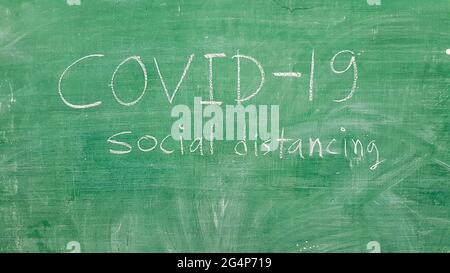 Covid-19 Wort geschrieben auf grüner Tafel mit weißer Kreide im Klassenzimmer Stockfoto