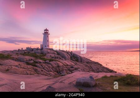 Ein dramatischer Sonnenuntergang, der zur blauen Stunde am Peggy's Cove Lighthouse Atlantic Coast Nova Scotia Canada festgehalten wird, während die Wellen des Ozeans die zerklüftete Küste umpflügen. Stockfoto