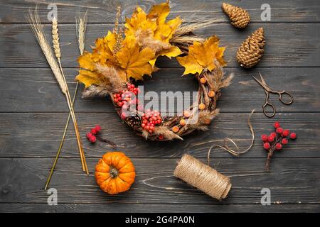 Schöner Herbstkranz mit Bastelbedarf auf Holzhintergrund Stockfoto
