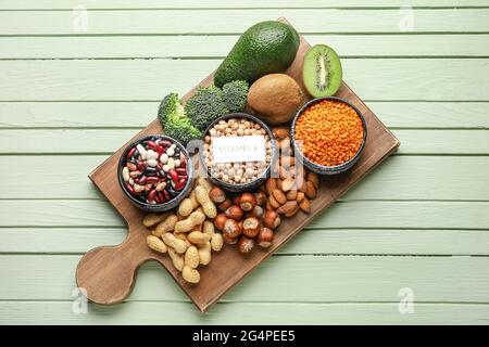 Brett mit gesunden Produkten reich an Vitamin E auf farbigem Holzhintergrund Stockfoto