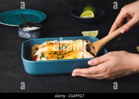 Frau mit heißem Enchilada in Backform Stockfoto