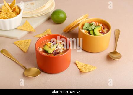 Schüsseln mit schmackhafter Hühnchen-Enchilada-Suppe auf farbigem Hintergrund Stockfoto