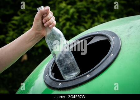 Werfen leere Glasflasche in grünen Papierkorb Abfallbehälter. Abfallsortierung Und Recycling-Konzept. Stockfoto