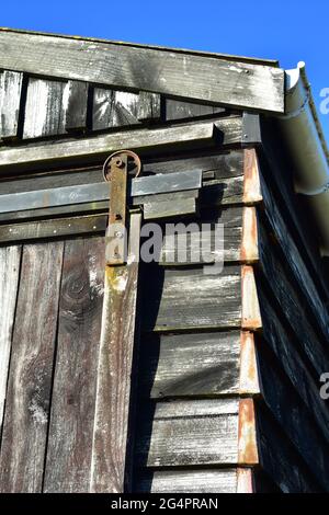 Gebäudeecke und Türgleis Detail auf alten verwitterten Holzscheune. Stockfoto