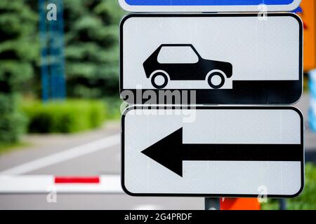 Straßenschild Parkplatz für Autos und ein Pfeil der Bewegungsrichtung auf dem Hintergrund einer Barriere. Stockfoto