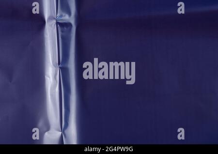 Blaue zerknitterte glänzende Oberfläche. Schuss von farbigen Verpackung Textur. Uneinheitlicher abstrakter Hintergrund mit Kopierbereich. Stockfoto