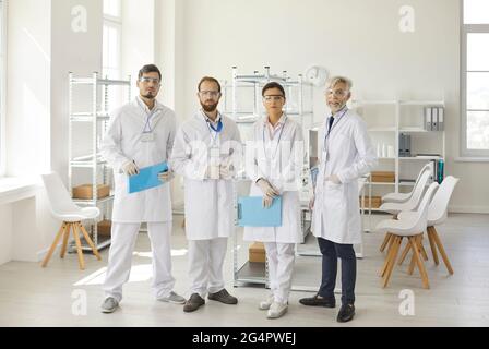 Diverse Wissenschaftler-Gruppe, die im Labor steht und auf das Kameraporträt schaut Stockfoto