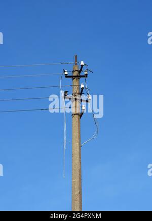 Ein Strommast, ein elektrischer Pfosten mit unterbrochenen Stromleitungen, beschädigte elektrische Kabel nach einem Sturm, als Ursache für Stromausfälle und den Stromausfall. Stockfoto