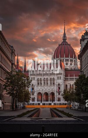 Budapest, Ungarn - das Denkmal der Nationalen Einheit und des Parlaments von Ungarn mit traditioneller gelber Straßenbahn und wunderschönen bunten Sonnenuntergangshimmel und Wolken Stockfoto