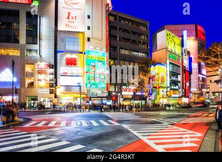 Tokio, Japan - 31. Dez 2019: Das berühmte Shibuya, das durch urbane Straßen kreuzt, kreuzt bei Sonnenuntergang mit hellen Anzeigenleuchten. Stockfoto