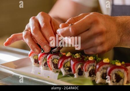Der Koch in der Restaurantküche verschönt leckere Sushi-Brötchen Stockfoto