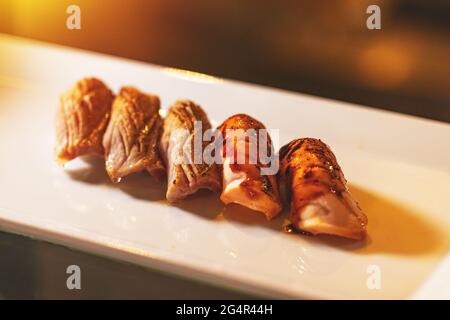 Gegrilltes Lachs-Sushi auf dem weißen Teller, Sushi auf warmen Gerichten Stockfoto