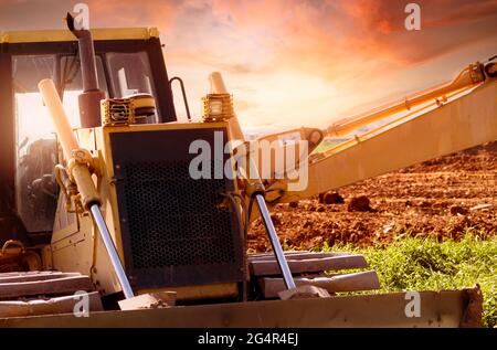 Selektiver Fokus auf Bulldozer auf unscharfen Hintergrund einer Baggerlader auf der Baustelle. Aushubfahrzeug. Hydraulikarm. Landentwicklungsgeschäft. Stockfoto