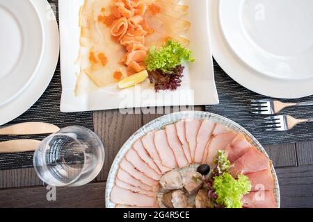 Schneiden von verschiedenen Arten von Fisch und Fleisch. Schneiden von roten und weißen Fischen. Festlicher Tisch Stockfoto