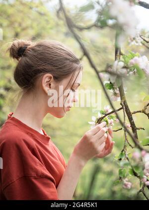 Ein junges Mädchen in einem blühenden Garten blickt auf blühende Bäume Stockfoto