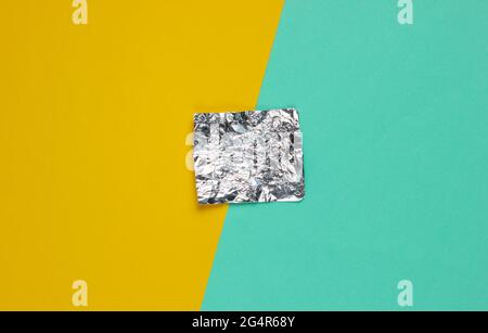 Ein Stück Folie auf farbigem Papierhintergrund. Draufsicht. Minimalismus-Konzept Stockfoto