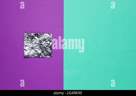 Ein Stück Folie auf farbigem Papierhintergrund. Draufsicht. Minimalismus-Konzept Stockfoto