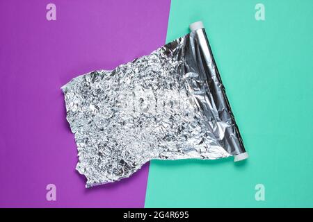 Eine Rolle zerknitterter Folie auf farbigem Hintergrund. Draufsicht Stockfoto