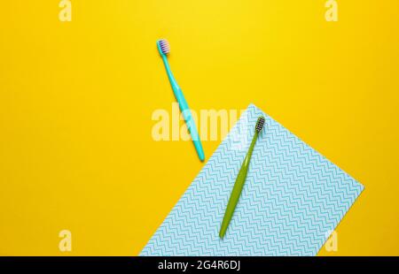 Zwei neue Zahnbürsten auf gelbblauem Papierhintergrund. Minimalismus Hygienekonzept Stockfoto