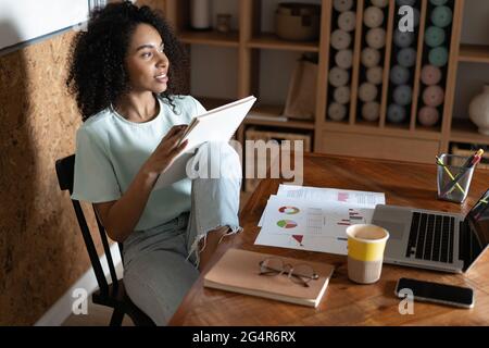 Junge kreative tausendjährige afroamerikanische Designerin, die im Büro arbeitet. Stockfoto
