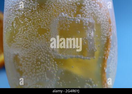 Limonadenwasser, das in einem Glas Eis und Orange geschieden wird, ist sehr nah. Macrophoto. Stockfoto