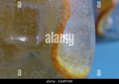 Limonadenwasser, das in einem Glas Eis und Orange geschieden wird, ist sehr nah. Macrophoto. Stockfoto