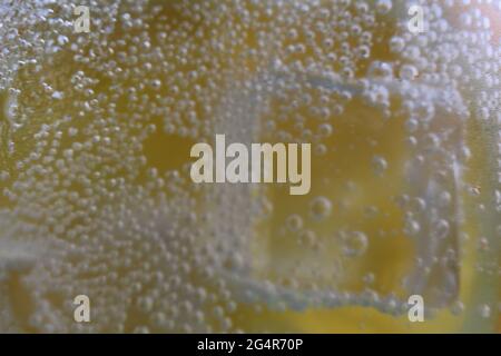 Limonadenwasser, das in einem Glas Eis und Orange geschieden wird, ist sehr nah. Macrophoto. Stockfoto