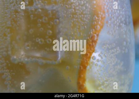 Limonadenwasser, das in einem Glas Eis und Orange geschieden wird, ist sehr nah. Macrophoto. Stockfoto