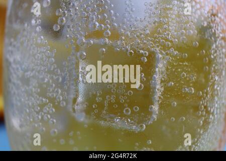 Limonadenwasser, das in einem Glas Eis und Orange geschieden wird, ist sehr nah. Macrophoto. Stockfoto