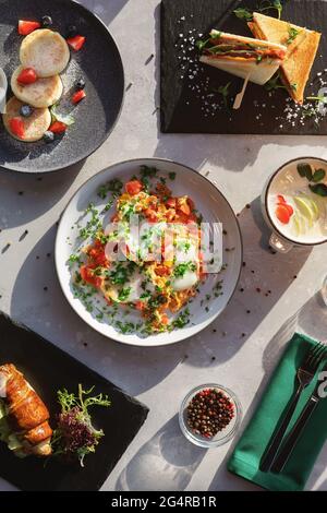 Verschiedene Frühstücksoptionen. Rührei, Käsekuchen, Milchbrei, Toast Stockfoto