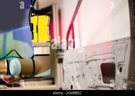 Der Roboterarm führt einen 3D-Scan des hergestellten Maschinenteils zur Qualitätskontrolle auf dem automatisierten Förderband im Werk durch. Stockfoto