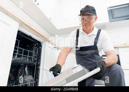 Service Klempner für die Reparatur und Installation von Geschirrspüler, männliche Arbeiter mit Werkzeug in Uniform. Stockfoto