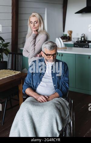 Ältere Frau, die in der Nähe des behinderten Mannes im Rollstuhl steht Stockfoto