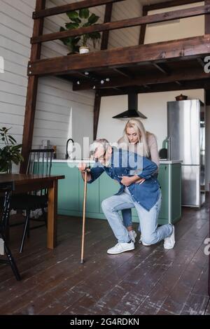 Ältere Frau hilft kranken Ehemann mit Krücke zu Hause Stockfoto