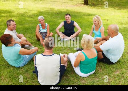 Eine fröhliche Gruppe von Erwachsenen sitzt auf dem Gras Stockfoto