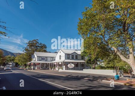 FRANSCHHOEK, SÜDAFRIKA - 12. APRIL 2021: Der historische Bahnhof von Franchhoek beherbergt heute Unternehmen. Menschen und Fahrzeuge sind sichtbar Stockfoto